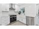 Modern kitchen features white cabinets, stainless steel appliances, and a farmhouse sink with stylish backsplash at 1868 Douglas Ave, Dunedin, FL 34698