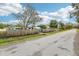 A street view showcasing the quaint neighborhood with mature trees and a classic wooden fence at 1868 Douglas Ave, Dunedin, FL 34698