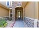 Close up of the front door with stone archway, well manicured front yard and stone facade elements at 19238 Climbing Aster Dr, Tampa, FL 33647