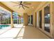 This covered patio features a ceiling fan, recessed lighting, a wall-mounted television and multiple glass doors to the home's interior at 19238 Climbing Aster Dr, Tampa, FL 33647