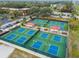 Aerial view of the community pickleball courts with blue surfaces, shaded seating, and mature trees at 2301 Grenoble Pl # 1, Sun City Center, FL 33573