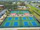 Aerial view of the community pickleball courts with blue surfaces, shaded seating, and palm trees at 2301 Grenoble Pl # 1, Sun City Center, FL 33573