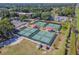 Aerial view of the community pickleball courts with blue surfaces, shaded seating, and nearby community buildings at 2301 Grenoble Pl # 1, Sun City Center, FL 33573