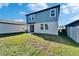 Blue and grey home with grassy backyard, patio and sliding glass doors at 3204 Fresno Pl, Zephyrhills, FL 33541
