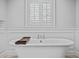 White bathtub with chrome hardware, a wooden tray, and wainscoting at 5010 S The Riviera St, Tampa, FL 33609