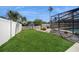 Manicured backyard showcasing a green lawn, white fence, and partial view of the pool enclosure at 6503 Santiago Ct, Apollo Beach, FL 33572