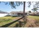 View of a home's backyard with a screened patio and white fence at 6818 Robinswood Ln, Tampa, FL 33634