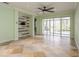 Open living room featuring travertine tile floor, accent wall and large sliding glass doors to the patio at 7313 Gaberia Rd, Trinity, FL 34655