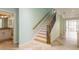 Staircase with decorative wrought iron spindles and a wood handrail, next to a tiled entryway at 7313 Gaberia Rd, Trinity, FL 34655