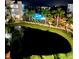 Nighttime view of a community pool surrounded by palm trees and overlooking a pond at 1026 Bellasol Way # 4403, Apollo Beach, FL 33572