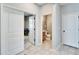 Hallway with open doorways, featuring a view of the game room and powder room, and tile floors at 10421 Laguna Plains Dr, Riverview, FL 33578