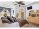 Main bedroom showcasing a ceiling fan, tray ceiling, ensuite access, and plenty of natural light at 16410 Ivy Lake Dr, Odessa, FL 33556