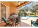 Outdoor dining area with a barbecue, table, and chairs, with a view of the sparkling pool at 16410 Ivy Lake Dr, Odessa, FL 33556