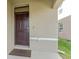 Close up of the front door and entry with dark brown door, stucco walls, and door bell at 16549 Secret Meadow Dr, Odessa, FL 33556