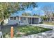 Single-story home with covered front porch and driveway, with a manicured lawn, under a blue sky at 1940 N Betty Ln, Clearwater, FL 33755