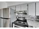 Close up of modern kitchen range with stainless steel hood and tile backsplash at 1940 N Betty Ln, Clearwater, FL 33755