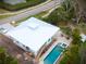 Aerial view of a coastal home with a pool and spa, metal roof, and lush landscaping at 406 Shore W Dr, Oldsmar, FL 34677