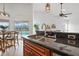 Kitchen featuring stainless steel sink, dark granite countertops, wood cabinets, and view of the backyard pool at 8914 Westbay Blvd, Tampa, FL 33615