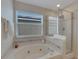 Bathroom featuring a garden tub, glass-enclosed shower, and a window with blinds for privacy at 9010 Grand Bayou Ct, Tampa, FL 33635