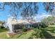Wide view of a lush, green backyard featuring a screened in patio and mature landscaping at 9376 French Quarters Cir, Weeki Wachee, FL 34613