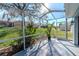 Screened in patio shows lush, green backyard and sunny skies, perfect for relaxing outdoors at 9376 French Quarters Cir, Weeki Wachee, FL 34613