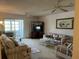 Bright living room with ceiling fan, comfortable seating, and sliding glass door to porch at 9815 47Th N Ave # 303, St Petersburg, FL 33708