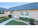 Charming home front entrance featuring a brick facade, well-maintained landscaping, and a gray metal roof at 11821 Boynton Ln, New Port Richey, FL 34654