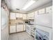 Cozy kitchen features white cabinets and appliances and a double basin sink with tiled flooring at 11821 Boynton Ln, New Port Richey, FL 34654