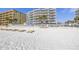 View of the beach with a beachfront condo with a pool in the background at 14700 Gulf Blvd # 405, Madeira Beach, FL 33708