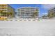 View of the beach with a beachfront condo with a pool in the background at 14700 Gulf Blvd # 405, Madeira Beach, FL 33708