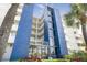 Modern condo building with blue accents, balconies, and lush landscaping at 14700 Gulf Blvd # 405, Madeira Beach, FL 33708