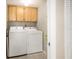 Functional laundry room featuring a washer, dryer, and overhead storage cabinets at 14700 Gulf Blvd # 405, Madeira Beach, FL 33708