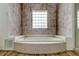 Bathroom highlighting a soaking tub with tile surround and a glass block window, providing privacy and style at 1547 Daylily Dr, Trinity, FL 34655