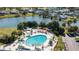 Aerial shot of a community pool and clubhouse overlooking a lake, with green umbrellas and a parking lot nearby at 2115 Hereford Dr, Sun City Center, FL 33573