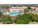 Aerial view of a large pool with sun umbrellas, surrounded by community buildings and green space at 2115 Hereford Dr, Sun City Center, FL 33573