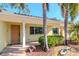 Welcoming one-story home featuring a covered porch, tropical landscaping, and a modern front door at 220 Garden S Cir, Dunedin, FL 34698