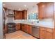 Bright kitchen boasts stainless appliances, wood cabinets, light countertops, modern backsplash, and hardwood floors at 220 Garden S Cir, Dunedin, FL 34698