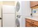 Laundry room features stacked washer and dryer next to a white refrigerator and wooden cabinetry at 220 Garden S Cir, Dunedin, FL 34698