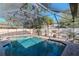 Serene screened-in pool surrounded by a brick patio, privacy fence, and mature trees for relaxation and recreation at 220 Garden S Cir, Dunedin, FL 34698