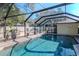 Backyard pool featuring a screened enclosure, brick patio, and lush landscaping, perfect for outdoor living at 220 Garden S Cir, Dunedin, FL 34698