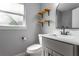 Updated bathroom with modern vanity, open wood shelving, and decorative round mirror at 2454 15Th N Ave, St Petersburg, FL 33713