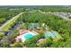 An aerial view of community featuring pool, clubhouse, basketball and tennis courts amidst lush trees at 31101 Wrencrest Dr, Wesley Chapel, FL 33543