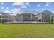 Spacious screened-in backyard featuring a pool, patio furniture, and a well-maintained lawn, ideal for outdoor living at 31101 Wrencrest Dr, Wesley Chapel, FL 33543