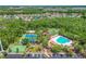 Aerial shot of community amenities featuring tennis courts, a playground, and a sparkling pool surrounded by trees at 31101 Wrencrest Dr, Wesley Chapel, FL 33543