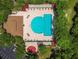 Aerial view of community pool and splashpad surrounded by green trees and lounge seating areas at 31101 Wrencrest Dr, Wesley Chapel, FL 33543