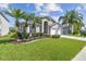 Beautiful single-story home with lush landscaping and a well-manicured lawn and tall palm trees at 31101 Wrencrest Dr, Wesley Chapel, FL 33543