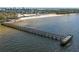An aerial view of a wooden pier stretching over calm waters towards a beautiful sandy beach at 3230 Mangrove Point Dr, Ruskin, FL 33570