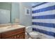 Bright bathroom features a wooden vanity, toilet, and a blue striped shower curtain at 3230 Mangrove Point Dr, Ruskin, FL 33570