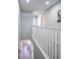 Bright hallway featuring gray carpet, white railings, and a view of the downstairs dining area at 3230 Mangrove Point Dr, Ruskin, FL 33570