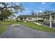 Daytime view of a well-maintained single-story home featuring a covered carport and a lush green lawn with mature trees at 330 Gloucester Blvd, Sun City Center, FL 33573